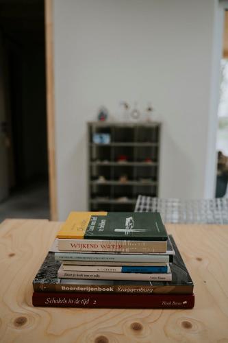 a stack of books sitting on top of a table at Bed en Brood in de Kapschuur - Boerderij de ZuiderKRIB in Kraggenburg