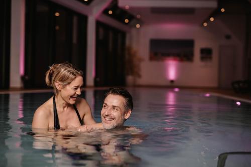 a man and woman swimming in a swimming pool at FAVORITE Parkhotel in Mainz