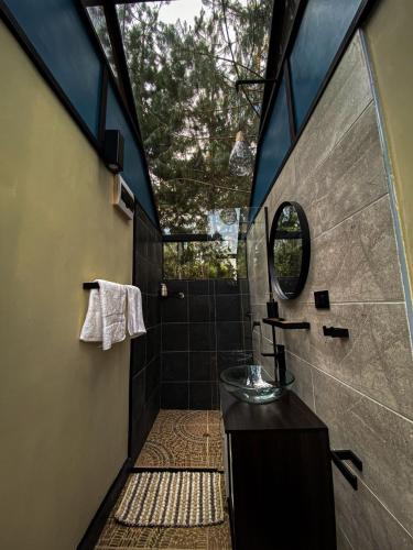 a bathroom with a shower with a sink and a mirror at Oasis Blue Oxapampa in Palmira