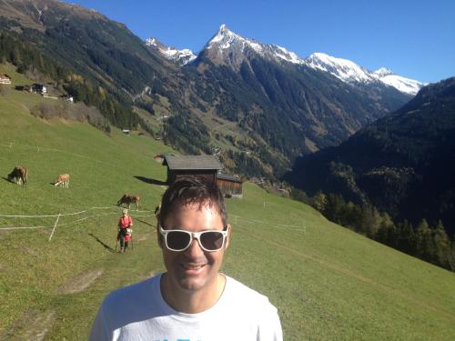 a man wearing sunglasses standing in a field with cows at Hotel Garni Erler in Mayrhofen