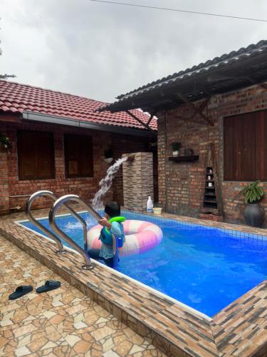 a child on a raft in a swimming pool at Lelangit Inn in Port Dickson