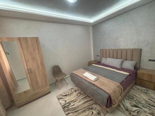 a bedroom with a bed and a chair and a mirror at appartement agadir in Agadir