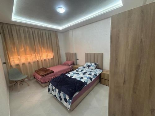 a bedroom with two beds and a window and a chair at appartement agadir in Agadir