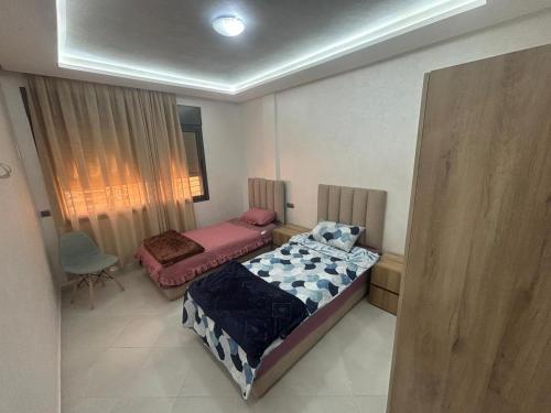 a small bedroom with two beds and a chair at appartement agadir in Agadir