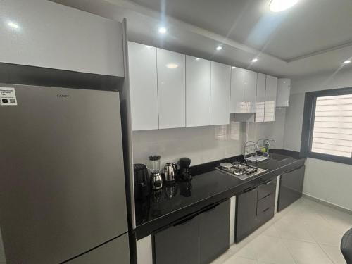 a kitchen with white cabinets and a black counter top at appartement agadir in Agadir