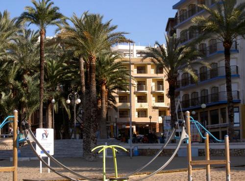 a playground in front of a building with palm trees at Aparthotel Milord's Suites in Benidorm