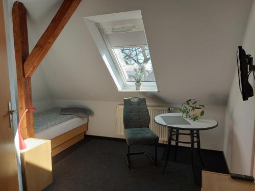 a small room with a table and a bed and a window at Zur Eiche - Pension in Böhlen