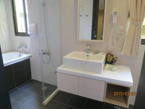 a white bathroom with a sink and a shower at 茶源旅店-潭暉魚池館 in Yuchi