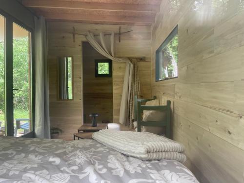 une chambre avec un lit dans une cabane en bois dans l'établissement Ti'Nid, cabane chaleureuse plongée dans la nature, à Montignac