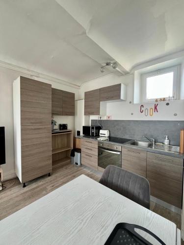 une grande cuisine avec des placards en bois et un évier dans l'établissement Lovely Normandy - Appt en centre ville de Bayeux, à Bayeux