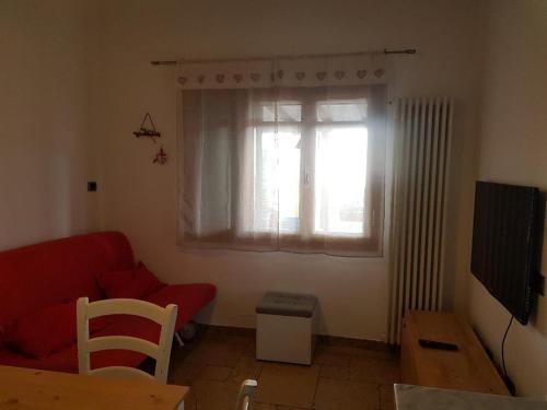 a living room with a red couch and a window at La Casa dei Nonni in Fabbiano