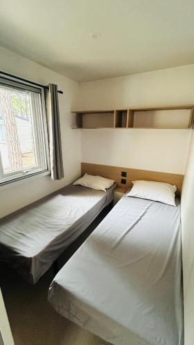 deux lits dans une chambre avec une fenêtre dans l'établissement L'Oasis des Pins, à Sète