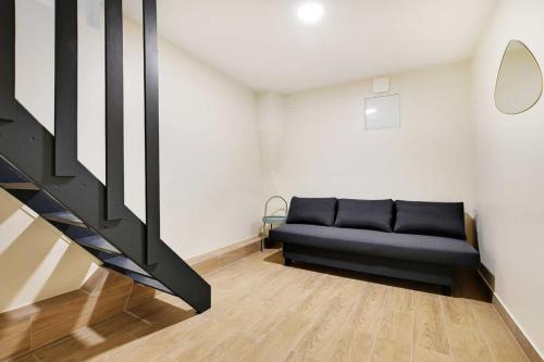 - un canapé noir dans une pièce avec un escalier dans l'établissement Cozy Apartment 2BR 6P - Boulets Nation, à Paris