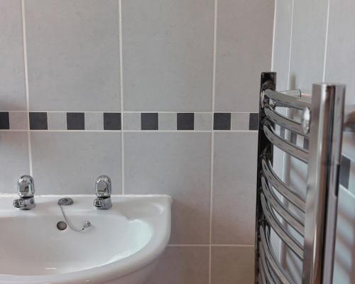 a bathroom with a white sink and black and white tiles at Honeysuckle Cottage in Killean