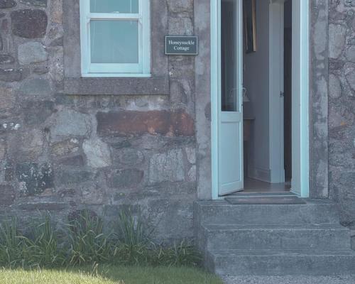 a door of a stone building with a sign on it at Honeysuckle Cottage in Killean