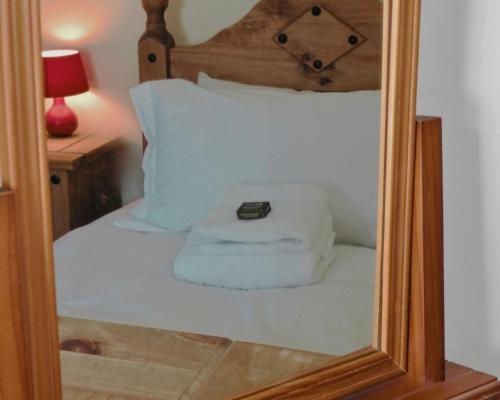 a mirror reflection of a bed with towels on it at Honeysuckle Cottage in Killean