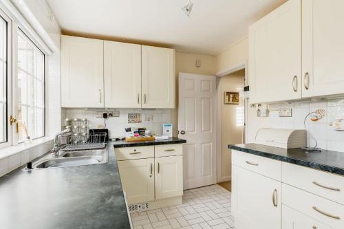 a kitchen with white cabinets and a sink at Chimneys - Old Town Poole Location, with Garden and Garage in Poole