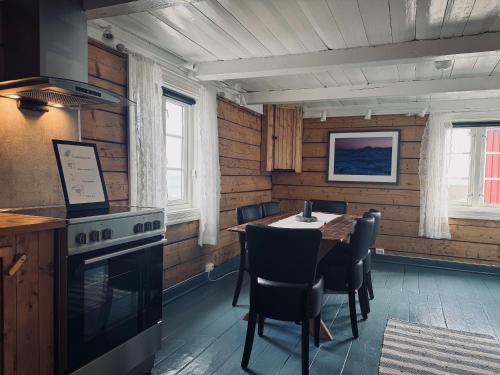 a kitchen with a table with chairs and a stove at Toppøy Rorbuer in Reine