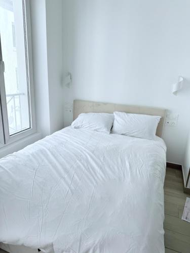 un lit blanc dans une chambre blanche avec une fenêtre dans l'établissement Central Paris Studio Clery 3 Walk to Marais Louvre, à Paris