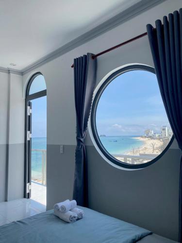 a bedroom with a bed and a window with a view of the beach at Phu Quy Vibes Villa - sát biển cạnh bãi tắm in Cù Lao Thu
