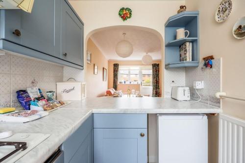a kitchen with blue cabinets and a white counter top at Anchorage - Quaint and Cosy Two-Bedroom House in Poole