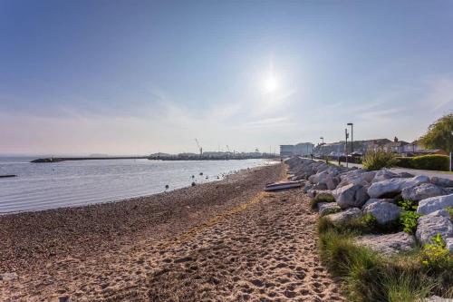 a beach with rocks and people on the water at Anchorage - Quaint and Cosy Two-Bedroom House in Poole