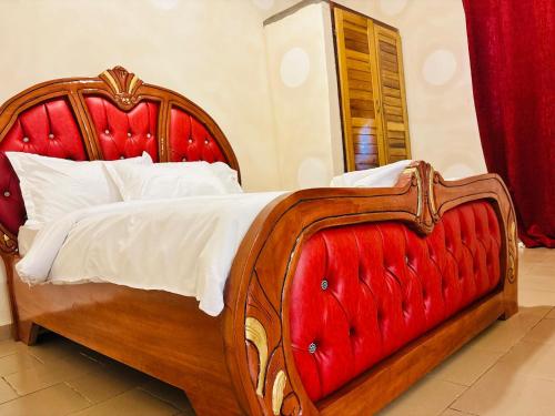 a bedroom with a wooden bed with a red headboard at HOTEL MAA MEVFOU Hmm in Yaoundé