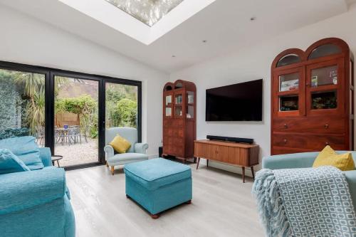 a living room with blue furniture and a flat screen tv at Middle Chine - Beautiful Garden and Spacious Living Space in Bournemouth