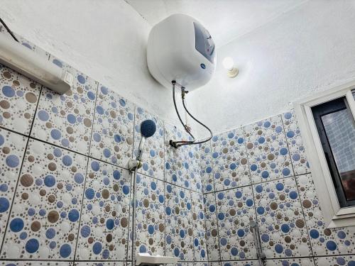a room with a shower with a light on the wall at HOTEL MAA MEVFOU Hmm in Yaoundé