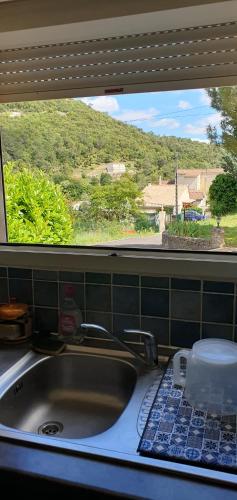 d'un évier de cuisine avec vue sur une fenêtre. dans l'établissement Maison en Cevennes, à La Barriére