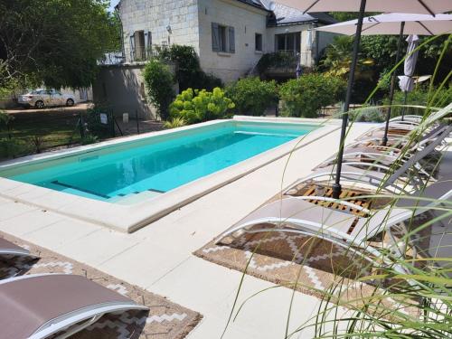 une piscine avec deux chaises et un parasol dans l'établissement La Cale de la Clauderie, à Rigny-Ussé