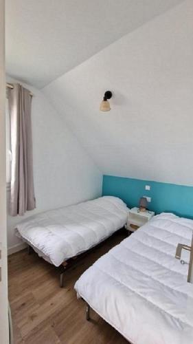 - une chambre avec 2 lits et une lampe sur le mur dans l'établissement La Cormorane, à Carnac