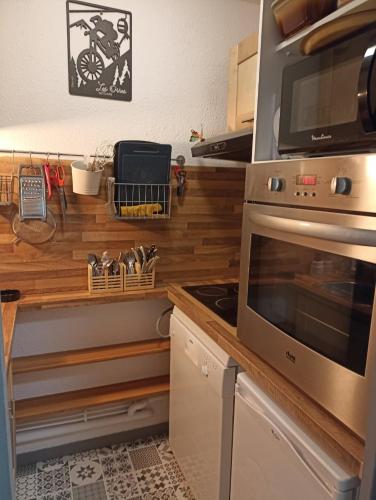 une cuisine avec une cuisinière et un micro-ondes dans l'établissement GRAND STUDIO 6 PERS 31m2 EN COEUR DE STATION, aux Orres