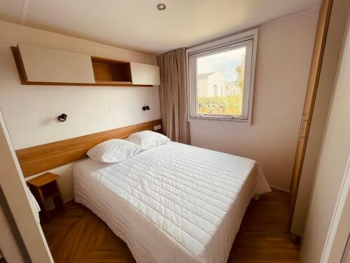 une chambre avec un lit blanc et une fenêtre dans l'établissement Mobil Home Bouginvilliers 5, à Valras-Plage