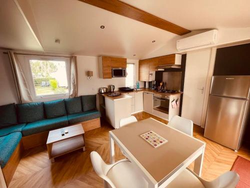 un salon avec un canapé et une table et une cuisine dans l'établissement Mobil Home Bouginvilliers 5, à Valras-Plage
