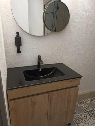 une salle de bain avec un lavabo noir et un miroir dans l'établissement GRAND STUDIO 6 PERS 31m2 EN COEUR DE STATION, aux Orres