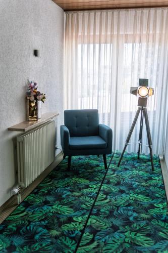 a room with a blue chair and a window at NEW Gästehaus Flora,Kitchen,TV,Free Parking,near Europa Park and Strasbourg in Hohberg