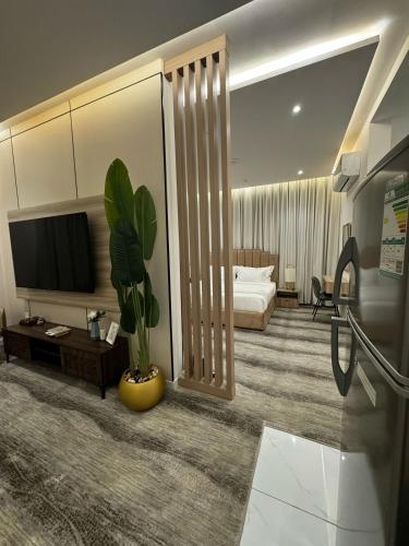 a living room with a television and a potted plant at شقة فندقية من غرفة و صالة مع بالكونة مطلة in Jeddah