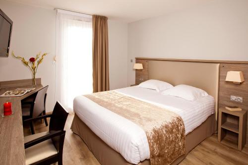 グルノーブルにあるセジュール＆アフェール グルノーブル マリ キュリの大きなベッドとデスクが備わるホテルルームです。