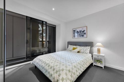 a bedroom with a bed and a large window at Stylish 2bed 2 bath pool & gym walk to Southern Cross in Melbourne