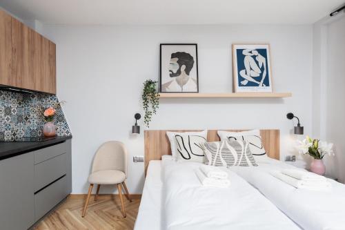 a white bedroom with a white bed and a chair at Nowy Hotel Monika - by Upstairs in Kraków