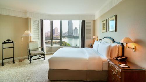 a hotel room with a bed and a large window at Marco Polo Xiamen in Xiamen