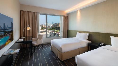 a hotel room with two beds and a window at Marco Polo Xiamen in Xiamen