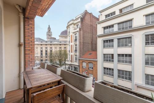 d'un balcon avec une table en bois et une vue sur la ville. dans l'établissement Grand Place - Appartement tout confort balcon, 4ch, à Lille