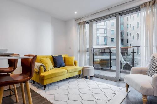 a living room with a yellow couch and a large window at Little Sea - Moments from Waterfront Restaurants in Poole