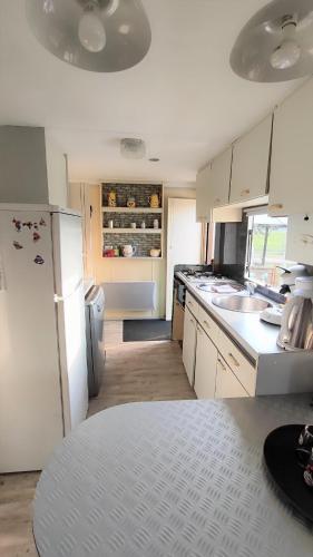 une cuisine avec des armoires blanches et un réfrigérateur blanc dans l'établissement Le Pré Vert - Hébergement pour 6 personnes, à Campigny