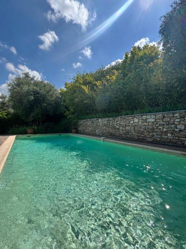 - une piscine avec un mur en pierre et de l'eau bleue dans l'établissement La maison aux oliviers, à Grasse