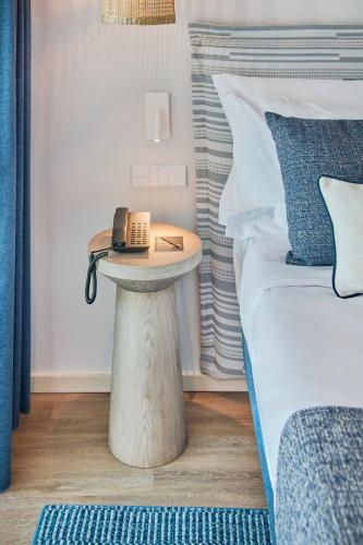a bed with a table with a phone on it next to a bed at The Editory by the Sea Lagos in Lagos
