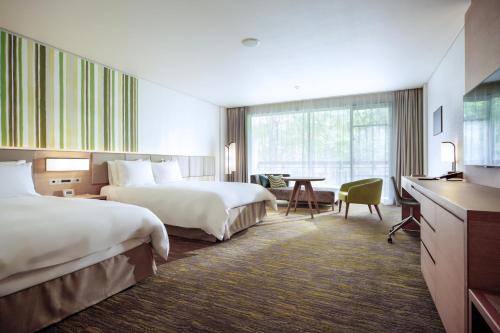 a hotel room with two beds and a desk at Holiday Inn Resort Shinano-Omachi Kuroyon by IHG in Omachi