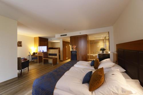 a large bed in a room with a living room at FAVORITE Parkhotel in Mainz